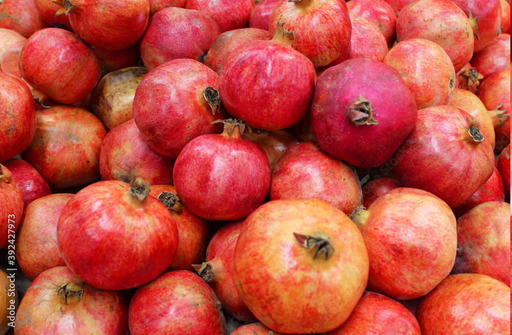 Pomegranate fruit background pattern. Whole pomegranate with flower. Fresh raw organic pomegranate fruit heap texture background. Ruby natural pomegranate close-up top view. on the market Pomegranate fruit background pattern. Whole pomegranate with flower. Fresh raw organic pomegranate fruit heap texture background. Ruby natural pomegranate close-up top view. on the market