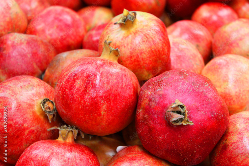Pomegranate fruit background pattern. Whole pomegranate with flower. Fresh raw organic pomegranate fruit heap texture background. Ruby natural pomegranate close-up top view. on the market Pomegranate fruit background pattern. Whole pomegranate with flower. Fresh raw organic pomegranate fruit heap texture background. Ruby natural pomegranate close-up top view. on the market