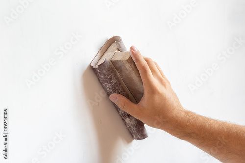 use sandpaper to sand the wall surface. Surface leveling, work inside the house. Copy space.