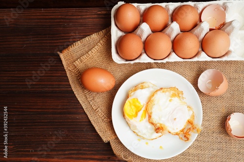Hot fried eggs and fresh eggs on the wooden table