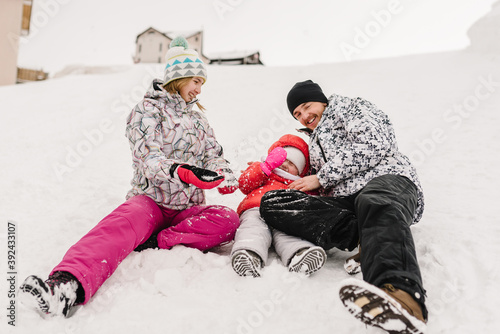 Portrait of happy family walking in a snow mountain in winter. Father, mother and children daughter are having fun and playing on snowy winter in park.