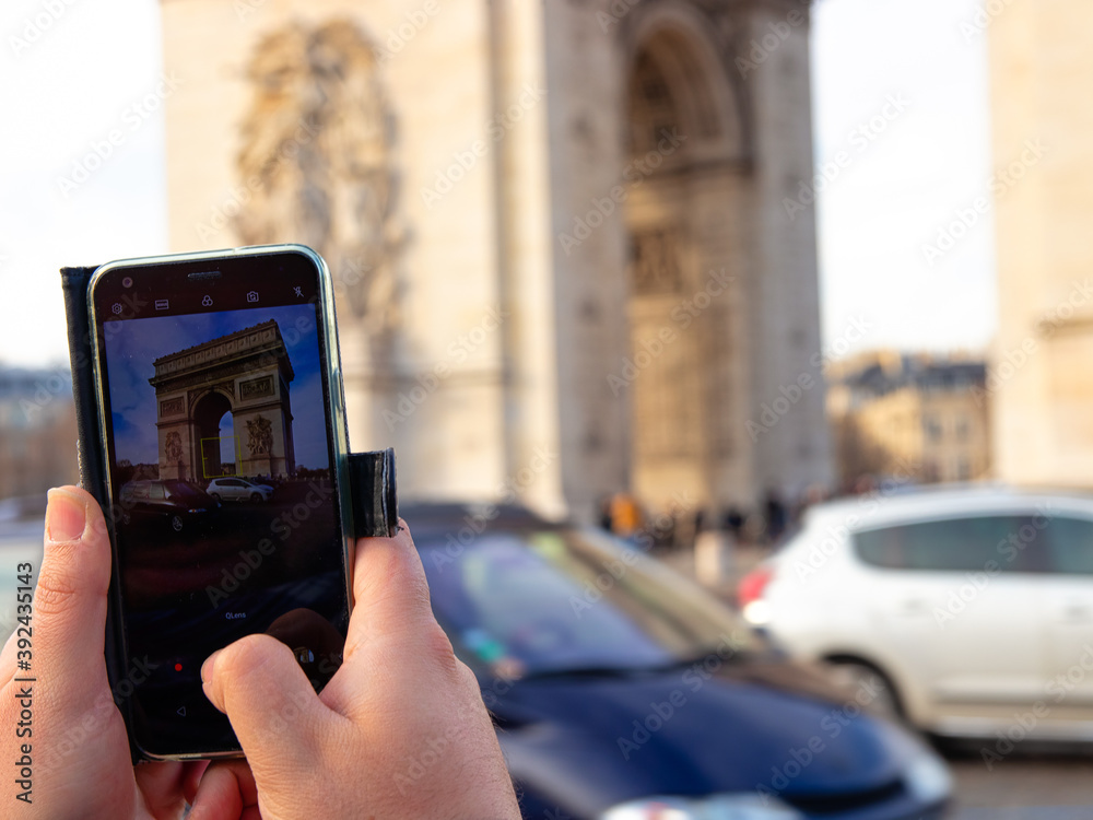 A tourist takes a photo of the Arc de Triomphe with his mobile phone