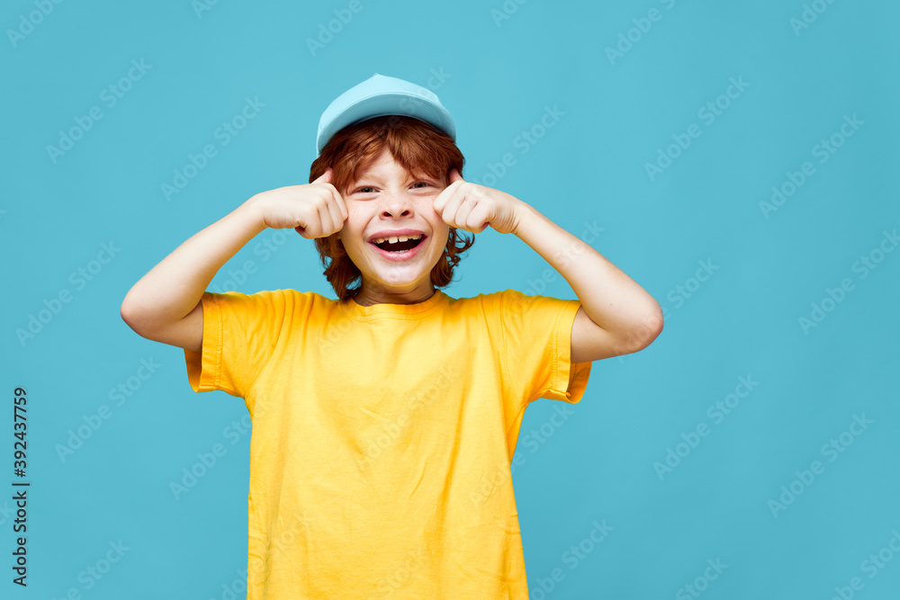 Cheerful boy wide smile cropped view yellow t-shirt cap blue background Copy Space Cheerful boy wide smile cropped view yellow t-shirt cap blue background Copy Space