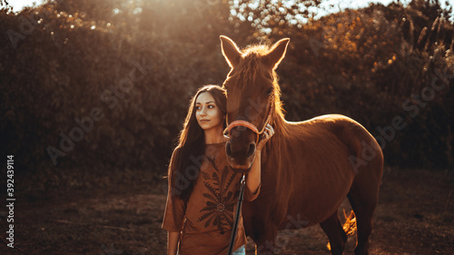 Chica joven andaluza ecuestre montando sobre caballo marron en un campo natural sin silla ni riendas en el sur de españa al atardecer feliz