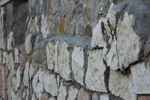 Background of flat stones and cement  decorative wall made of natural materials. Stony hard surface made of parts of different sizes and shapes with a sandy tint