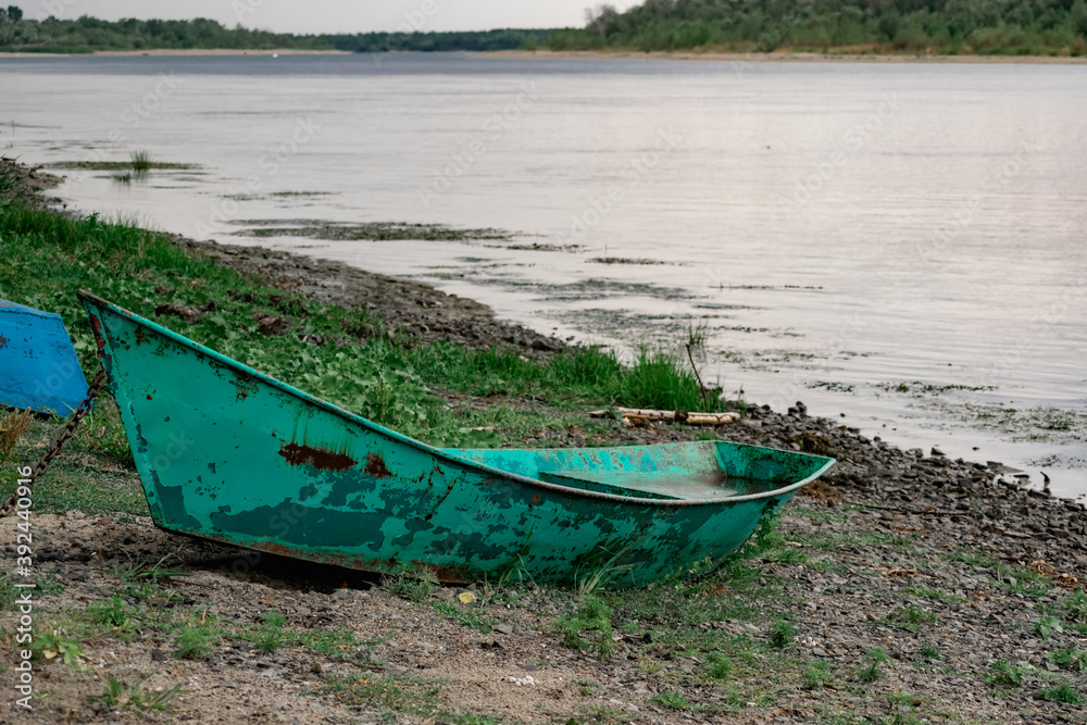 Old boats made of wood and metal on the river Bank among rocks and vegetation. Parked water transport in nature. Simple landscape. Old boats made of wood and metal on the river Bank among rocks and vegetation. Parked water transport in nature. Simple landscape.
