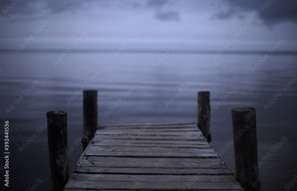 Fototapeta premium cloudy landscape, on the horizon of the sea and sky an old wooden bridge for fishermen and small boats. Melancholic mood and calmness. minimalism in nature. calm water and sky