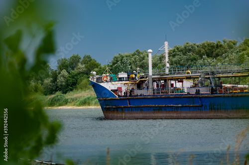 Navigable color barge floating on the river, carrying cargo in the Rostov region. Summer in nature on the don river and passing by, large and long ships made of painted metal