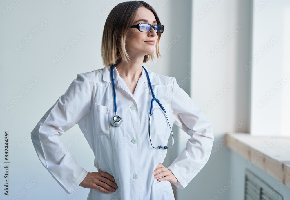 Woman with professional stethoscope Doctor in medical gown in bright room Woman with professional stethoscope Doctor in medical gown in bright room