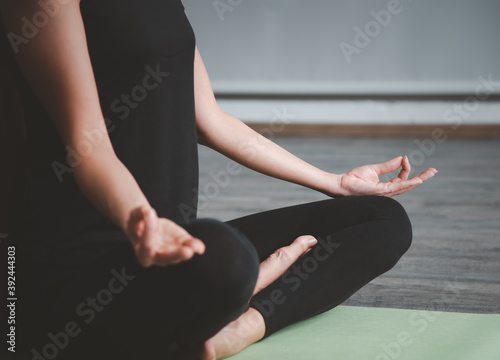 Young woman practicing yoga in a room with her left hand focus on.