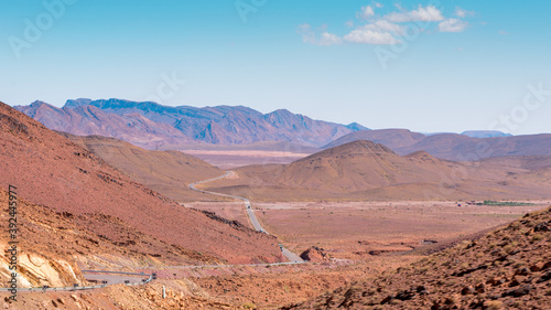 Otherworldly Landscape with mountains and reddish land and infinite road that crosses them. High Atlas, Morocco.