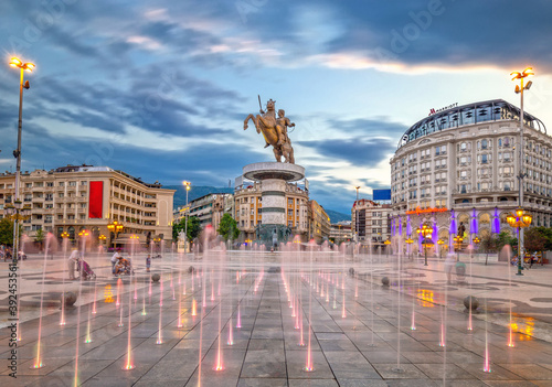 Skopje, North Macedonia - 01.08.2020: Square Macedonia in Skopje at sunset with dancing illuminated fountains and statue of Alexander the Great (warrior on horse) at background photo