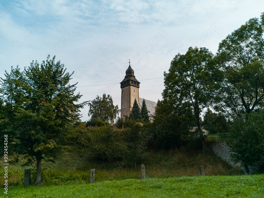 Small church with big tower behind park in small village