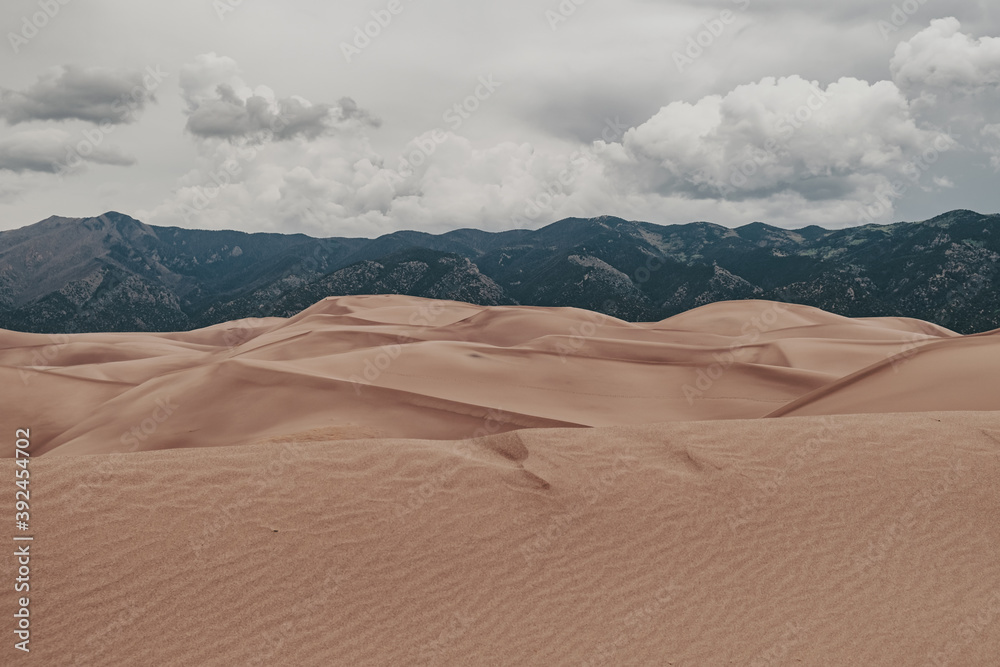 A view of giant desert sand dunes and the surrounding Sangre De Cristo Mountains in Great Sand Dunes National Park in Colorado, USA.