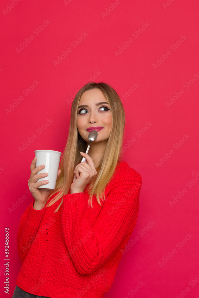 Cute Woman In Red Sweater Is Holding Cup And Spoon And Looking Away Cute Woman In Red Sweater Is Holding Cup And Spoon And Looking Away