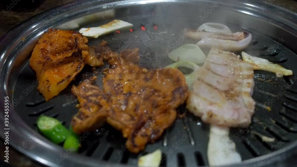 asian woman in japanese bbq restaurant using mobile smart phone taking photo of food for upload to social network.