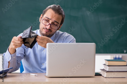 Young underpaid male teacher in the classroom photo