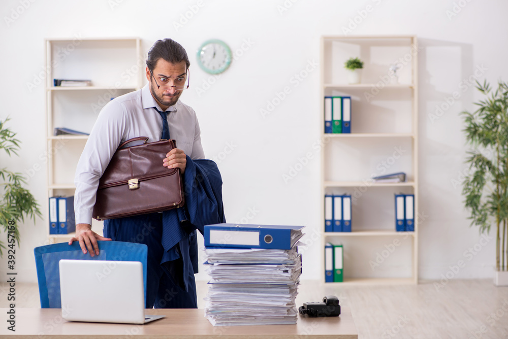 Young businessman unhappy with excessive work in the office Young businessman unhappy with excessive work in the office