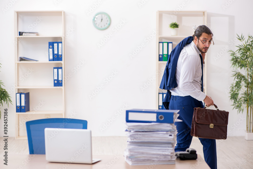 Young businessman unhappy with excessive work in the office Young businessman unhappy with excessive work in the office