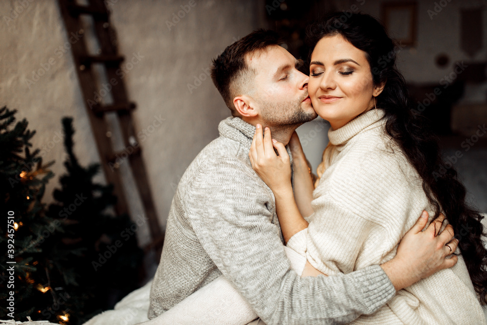 Adorable couple sit near the Christmas tree at home, cuddling, romantic husband with lovely wife spend winter holidays together, enjoy happy moments, New Year celebration concept Adorable couple sit near the Christmas tree at home, cuddling, romantic husband with lovely wife spend winter holidays together, enjoy happy moments, New Year celebration concept