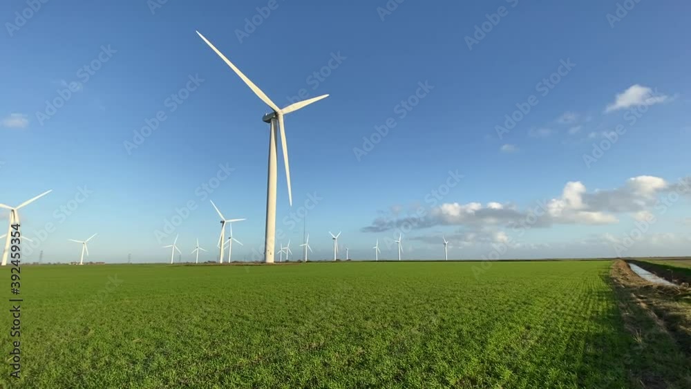 Wind farm turbines that produce electricity energy. Windmill Wind power technology sustainable Wind turbines standing in green field - stock footage Wind farm turbines that produce electricity energy. Windmill Wind power technology sustainable Wind turbines standing in green field - stock footage