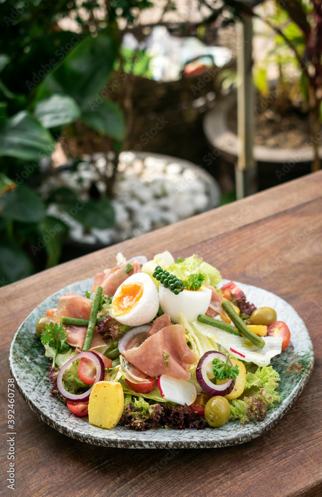 nicoise style healthy organic salad with egg and ham outdoors