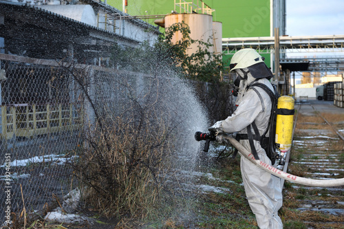 Rescuer in protective ensemble watering plant territory with syringe - Rescue team training of chemical decontamination © Yurii Zushchyk