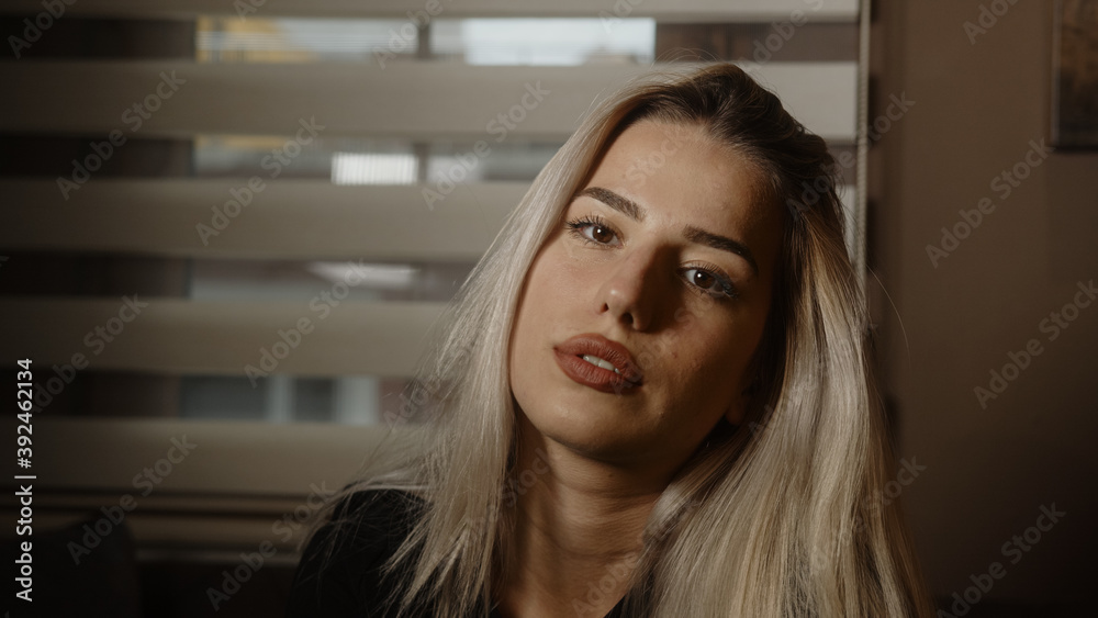 Young blonde charming attractive pretty blonde hair woman looking at camera in office or at home, dressed in blond black Young blonde charming attractive pretty blonde hair woman looking at camera in office or at home, dressed in blond black
