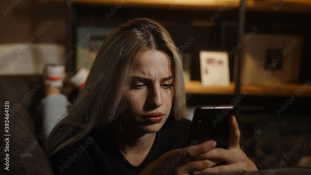 Young unhappy blonde woman lying on sofa received a bad message or had a bad incident on the phone Young unhappy blonde woman lying on sofa received a bad message or had a bad incident on the phone