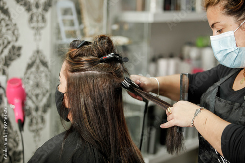 Woman with face mask getting a fresh style at a hair salon. Woman getting a hair wash. Hairdressing concept.