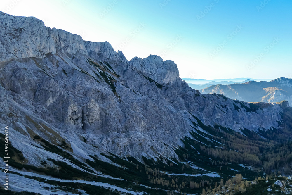 Fototapeta premium A new day breaking in in Hochschwab region in Austrian Alps. The flora overgrowing the slopes is golden. Golden grass. Autumn vibes. Sun is rising from behind a steep mountain chain. Wilderness