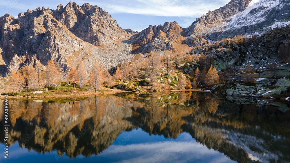 Colorful autumn view of small mountain lake with water reflection. Morning light. Alps, Italy, Europe.