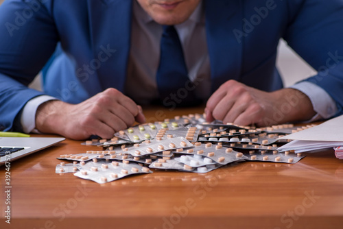 Young male sick employee suffering at workplace