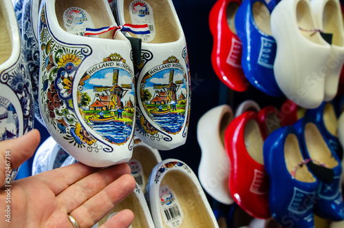 Kinderdijk, The Netherlands, August 2019. Souvenir Dutch clogs, produced in different shapes and colors, make a good show in the display. The tourist's hand touches them to observe them. photo