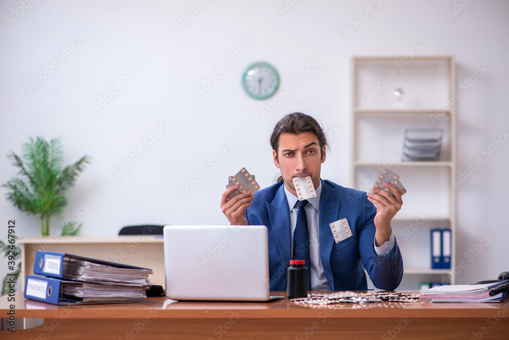 Young male sick employee suffering at workplace Young male sick employee suffering at workplace