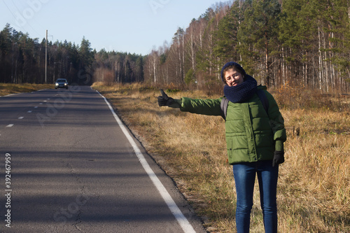 girl tourist hitchhiking, catches a car on the road