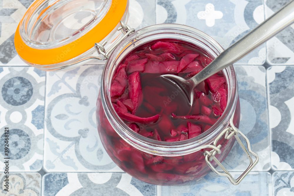 Pickled red cabbage in a clip glass storage jar.  On a blue tile background