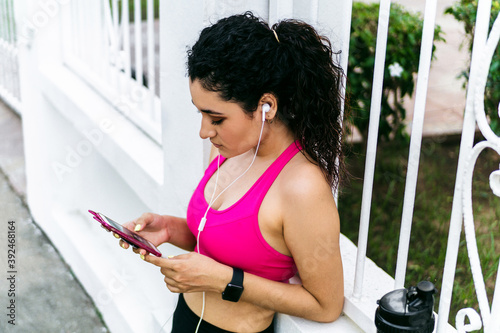 Closeup shot of young female texting on the phone and getting ready for workout outdoors,. communication concept.