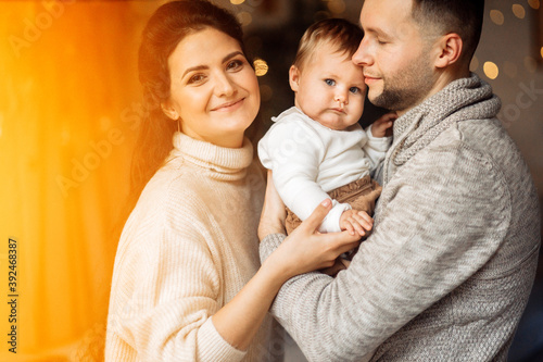 Lovely parents with little daughter spend winter holidays at home, loving father hold cute toddler in arms, enjoy tender moments, Christmas and new year celebration concept