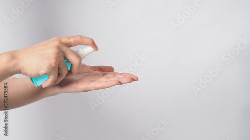 Hand is holding Alcohol Spray and wash the other hand on white background.