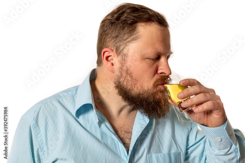 Solid bearded man in shirt tasting whisky studio portrait