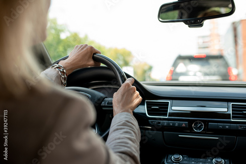 Hands of contemporary mature businesswoman holding by steer while driving