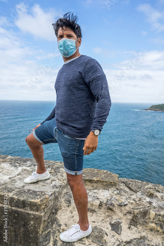 man posing with a blue surgical mask with the horizon in the background
