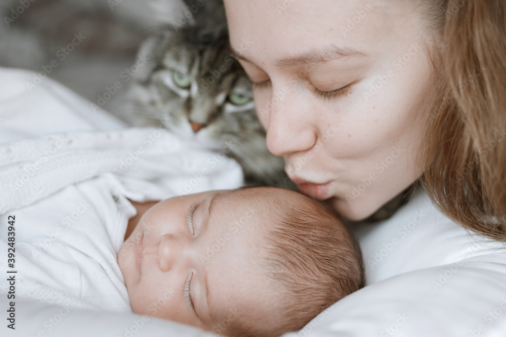 Adorable child in a white sunny bedroom. Baby is resting in bed. Family morning at home. Loving mom carying of her newborn baby. Adorable child in a white sunny bedroom. Baby is resting in bed. Family morning at home. Loving mom carying of her newborn baby.