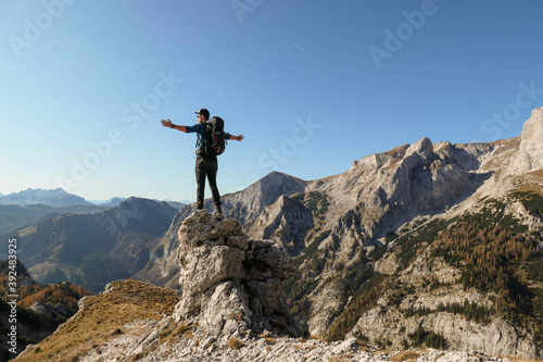 A man standing on top of a sharp  pointy boulder in Hochschwab region  Austrian Alps. The steep mountain wall in front look very dangerous. High mountaineering. Autumn vibes. Adventure and freedom