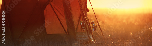 carp rods stand next to the tent in the sun