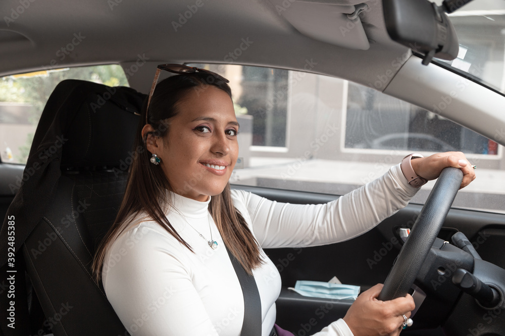 beautiful latin woman with straight hair and accessories, sitting in a car while holding the steering wheel, wearing seat belt, modern lifestyle