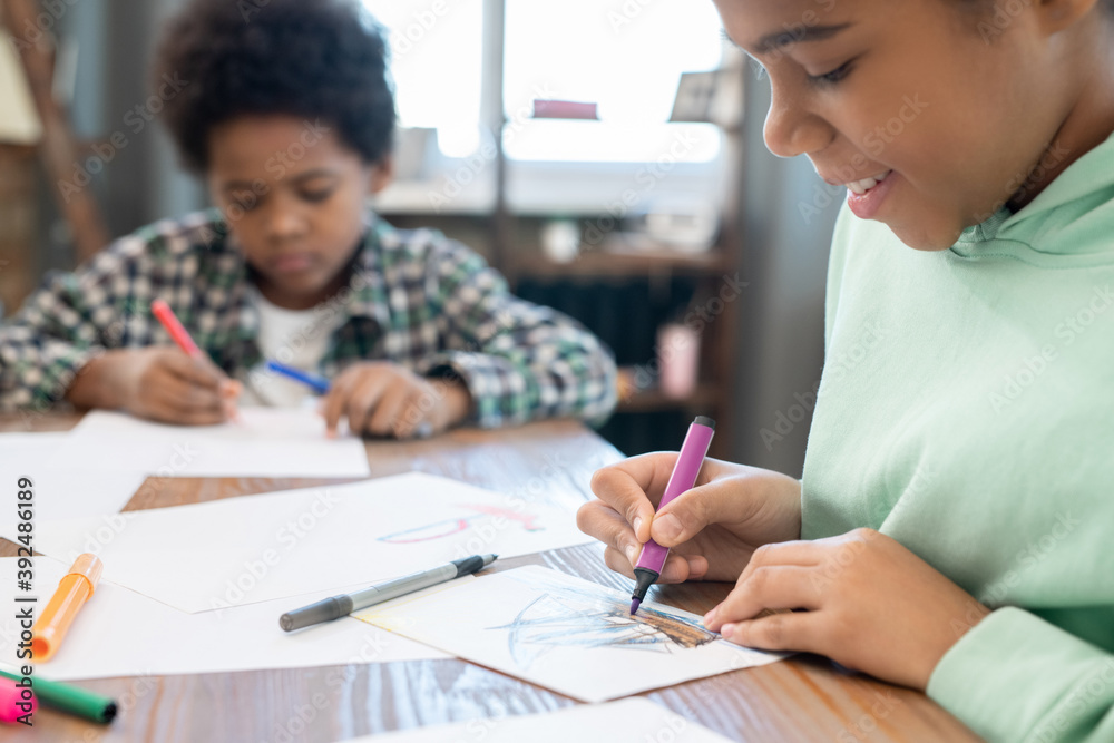 Diligent schoolgirl and her cute brother drawing with highlighters on paper Diligent schoolgirl and her cute brother drawing with highlighters on paper