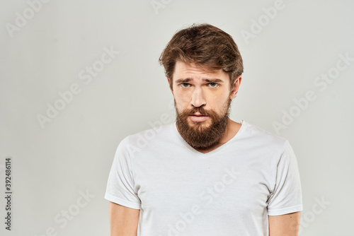 man in white t-shirt gesturing with his hands studio dissatisfaction lifestyle light background