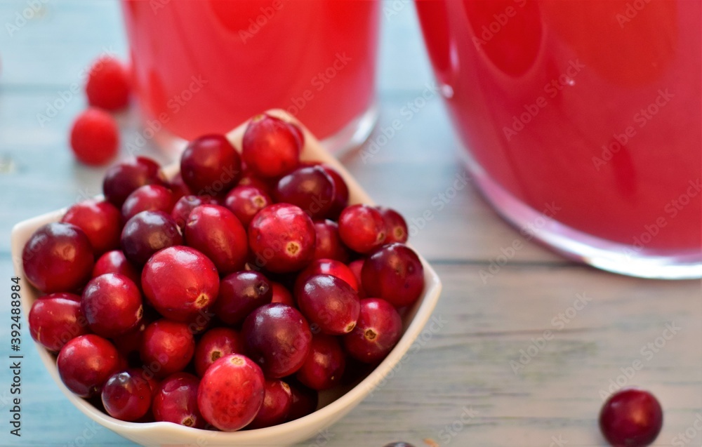 ripe raspberries and cranberries, a drink in a decanter and a glass on a wooden table ripe raspberries and cranberries, a drink in a decanter and a glass on a wooden table